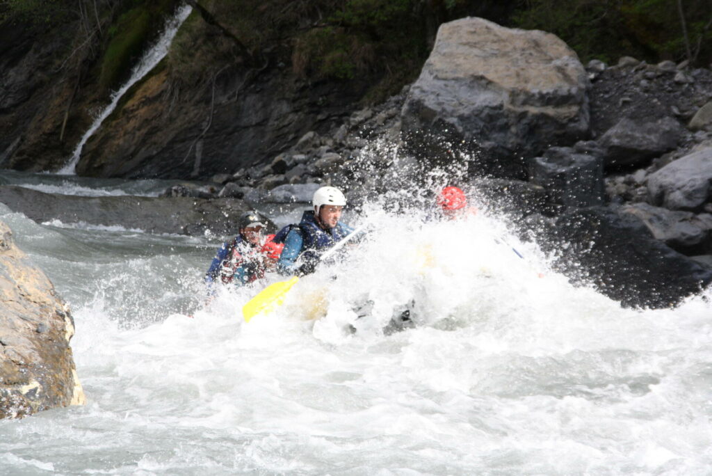 un raft qui prend une grosse vague  dans les alpes