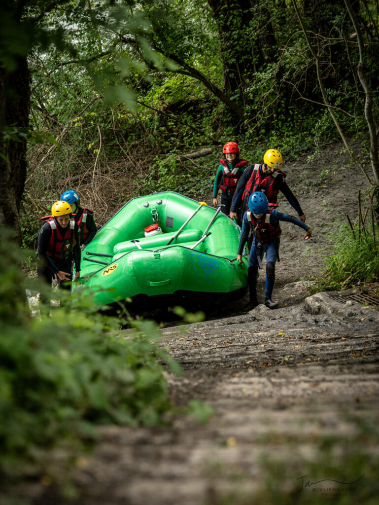 Un groupe de EVJF qui porte un raft vert en Ubaye